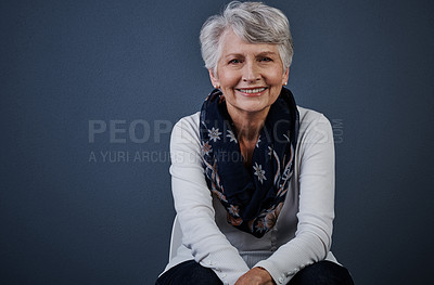 Buy stock photo Studio shot of a cheerful elderly woman sitting down and looking straight into the camera while smiling