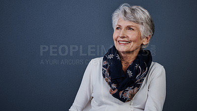 Buy stock photo Studio shot of cheerful elderly woman sitting down and looking into the distance while smiling