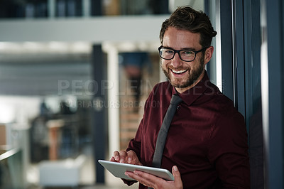 Buy stock photo Shot of a young businessman using a digital tablet in a modern office