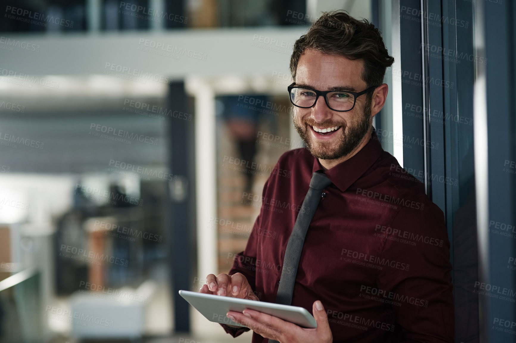 Buy stock photo Shot of a young businessman using a digital tablet in a modern office