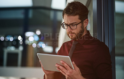 Buy stock photo Shot of a young businessman using a digital tablet in a modern office