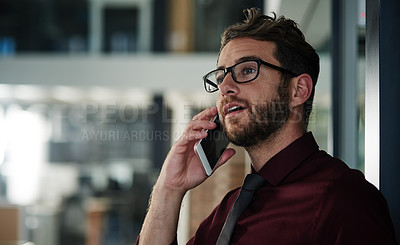 Buy stock photo Shot of a young businessman using a mobile phone in a modern office