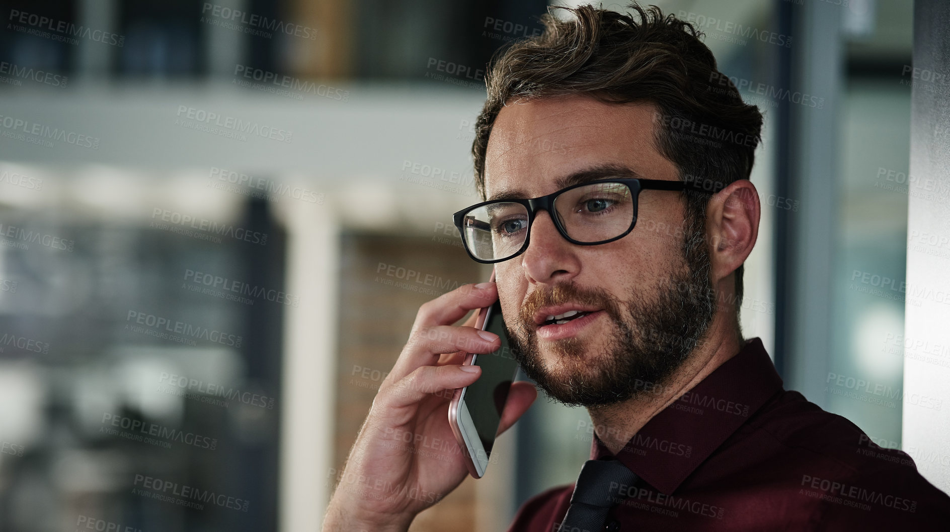 Buy stock photo Shot of a young businessman using a mobile phone in a modern office