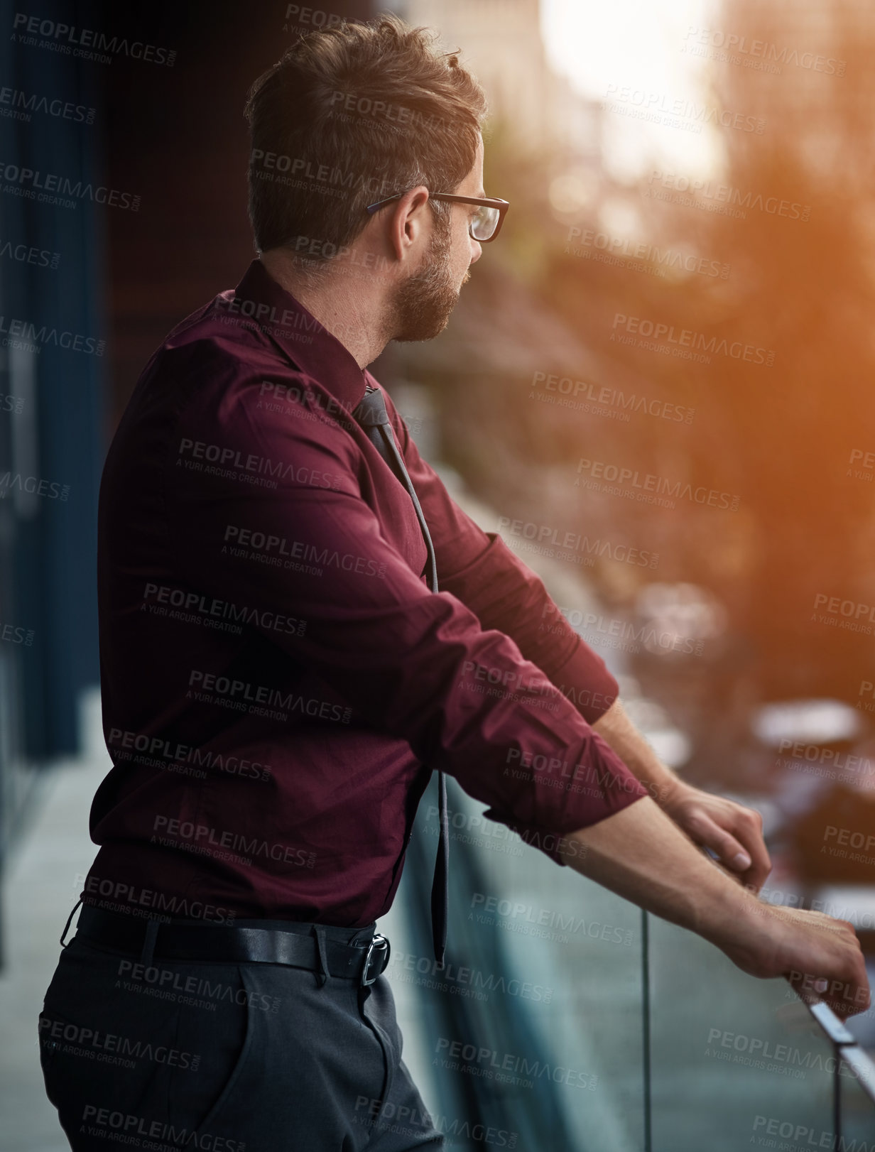 Buy stock photo Shot of a young businessman standing outside on the balcony of an office