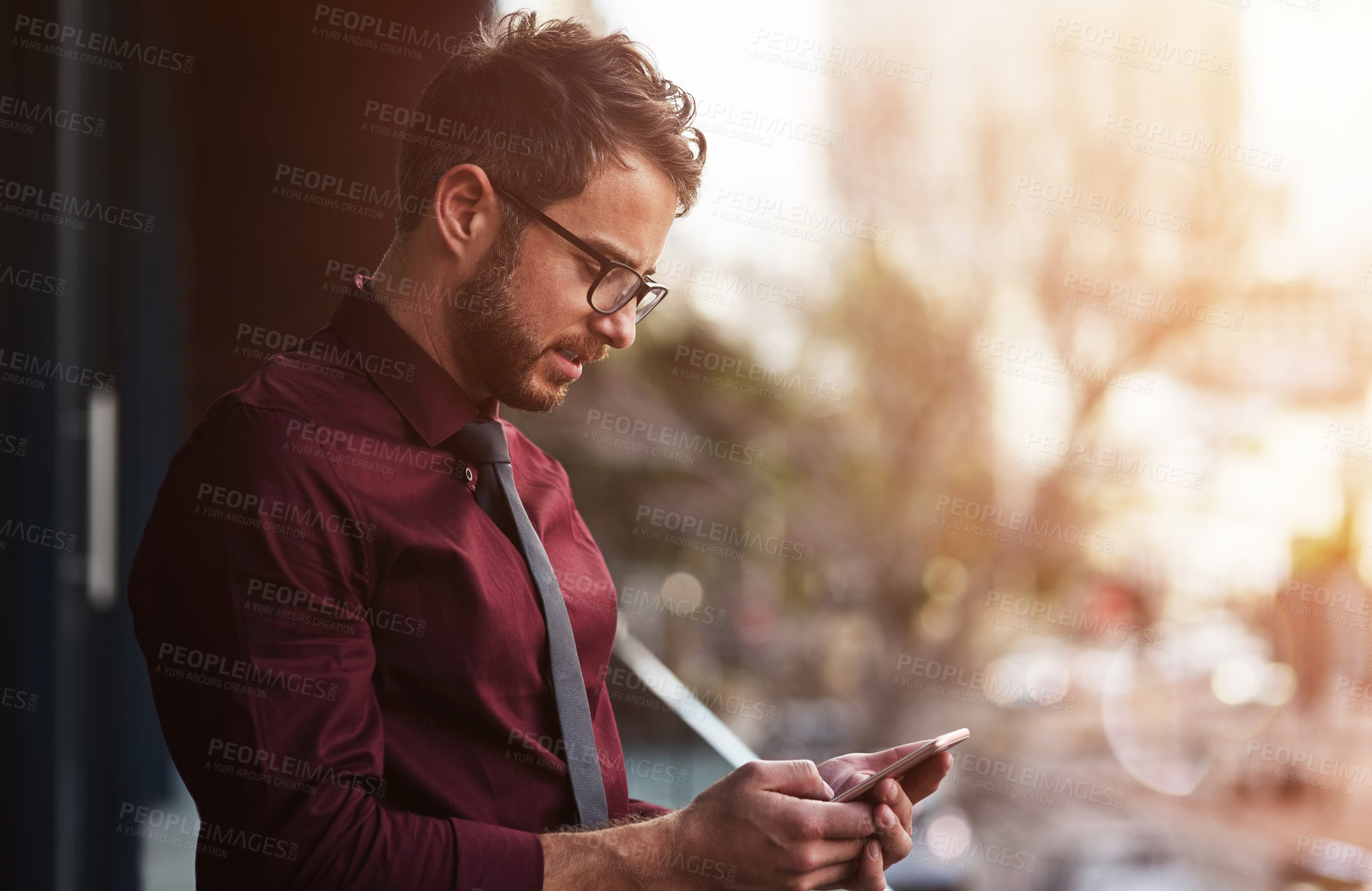 Buy stock photo Shot of a young businessman using a mobile phone on the balcony of an office