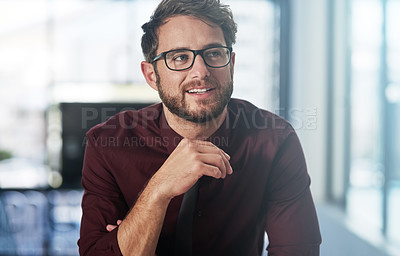 Buy stock photo Shot of a confident young businessman looking thoughtful in a modern office