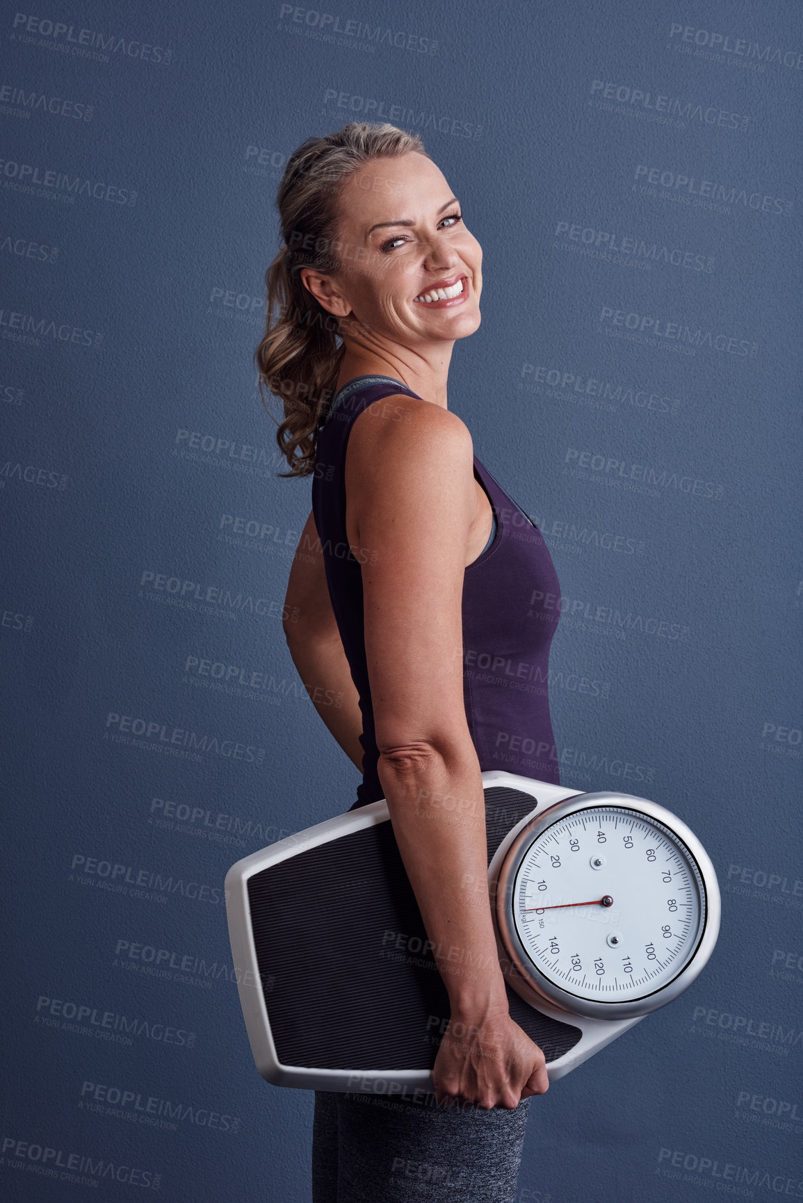 Buy stock photo Studio portrait of an attractive mature woman holding a weightscale against a blue background