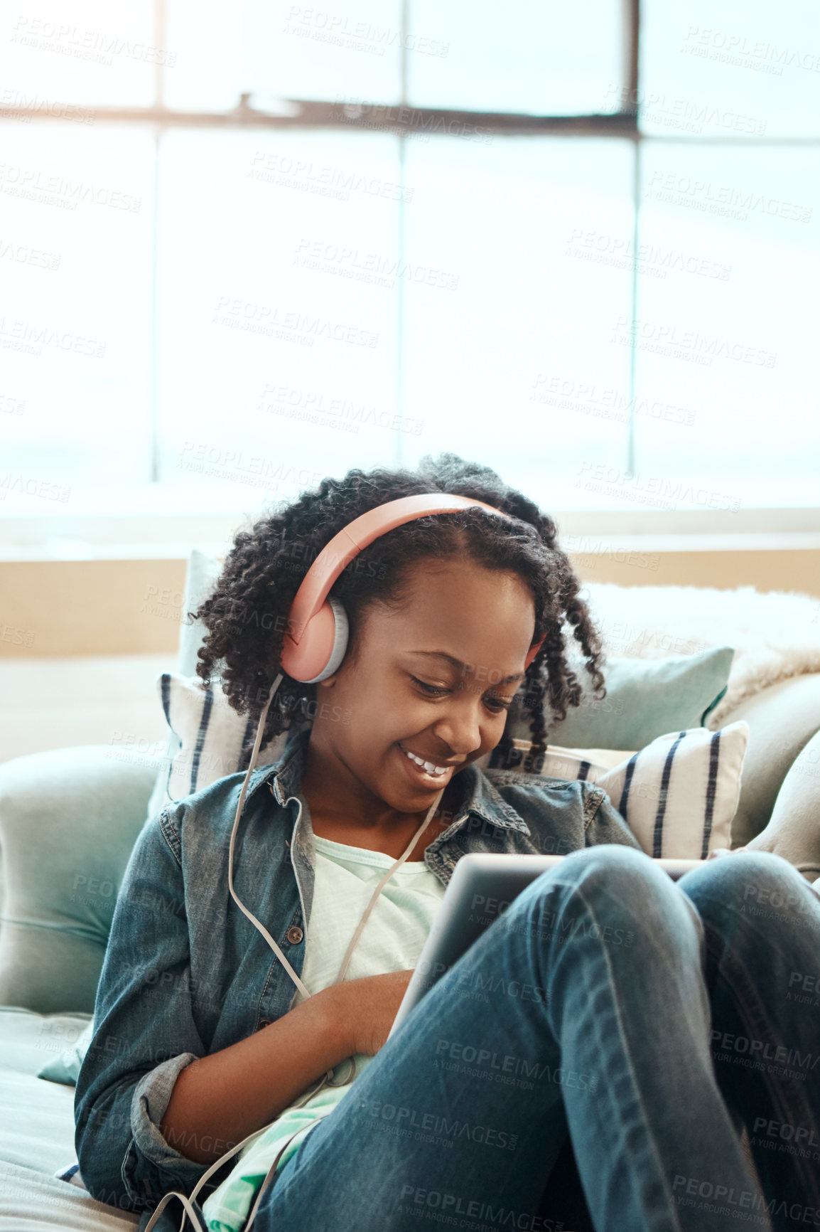 Buy stock photo Digital tablet, sofa and girl with headphones relaxing while listening to music, radio or podcast. Rest, technology and African child watching a video or movie on mobile device in living room at home