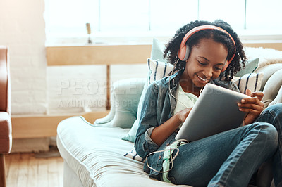 Buy stock photo Headphones, tablet and woman on the sofa to relax while listening to music, radio or podcast. Rest, technology and African lady watching a video or movie on mobile device in her living room at home.