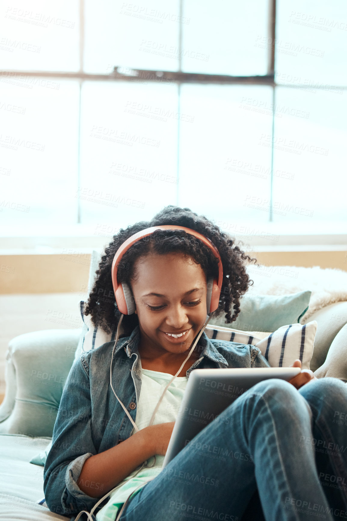 Buy stock photo Happy girl, headphones and entertainment with tablet on sofa for online streaming or listening to music at home. Young female person, child or teenager in relax with smile on technology for audio