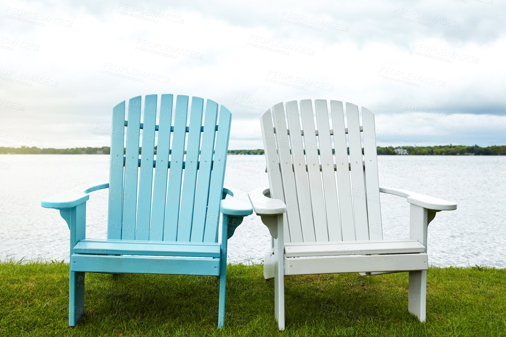 Buy stock photo Shot of two empty chairs alongside a lake