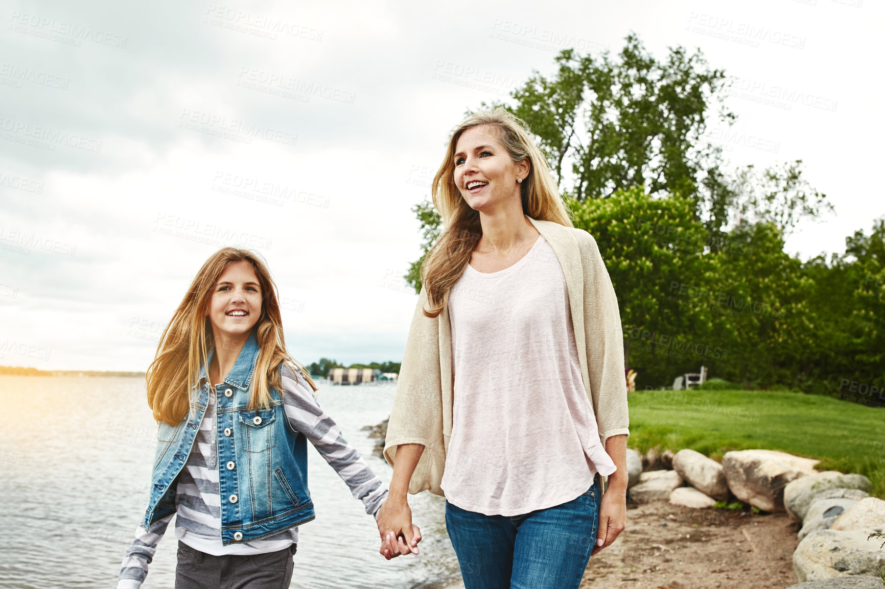 Buy stock photo Holding hands, lake or walking with mother and girl child outdoor in nature together for bonding. Family, love or summer with woman and daughter by water in park for security, support or trust