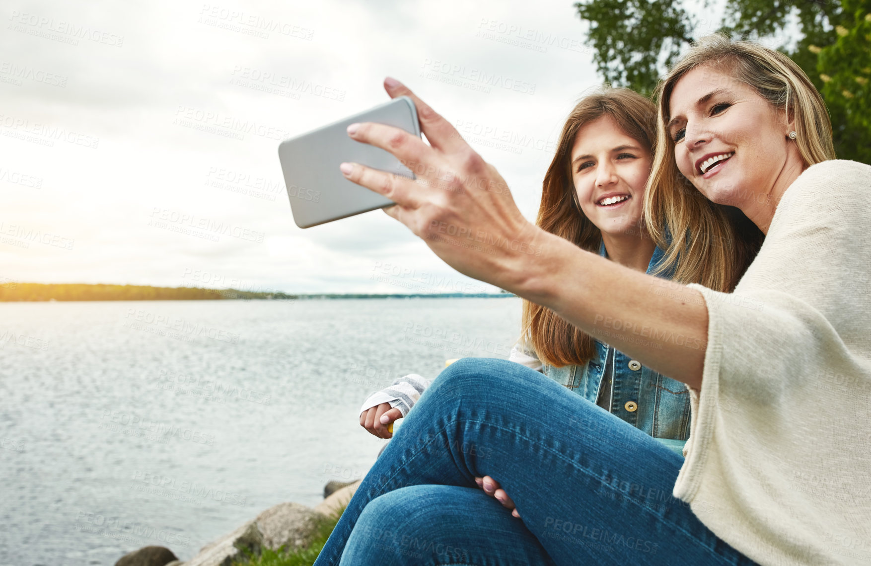 Buy stock photo Shot of a mother and her daughter taking a selfie together outdoors