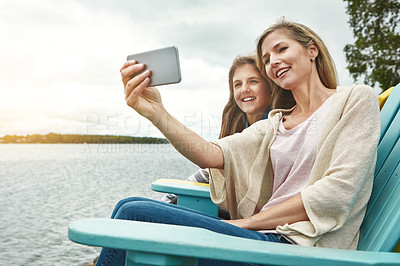 Buy stock photo Shot of a mother and her daughter taking a selfie together outdoors