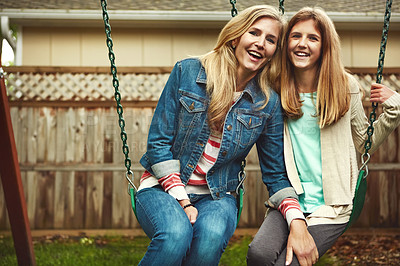 Buy stock photo Shot of a mother and her daughter playing on a swing in their backyard