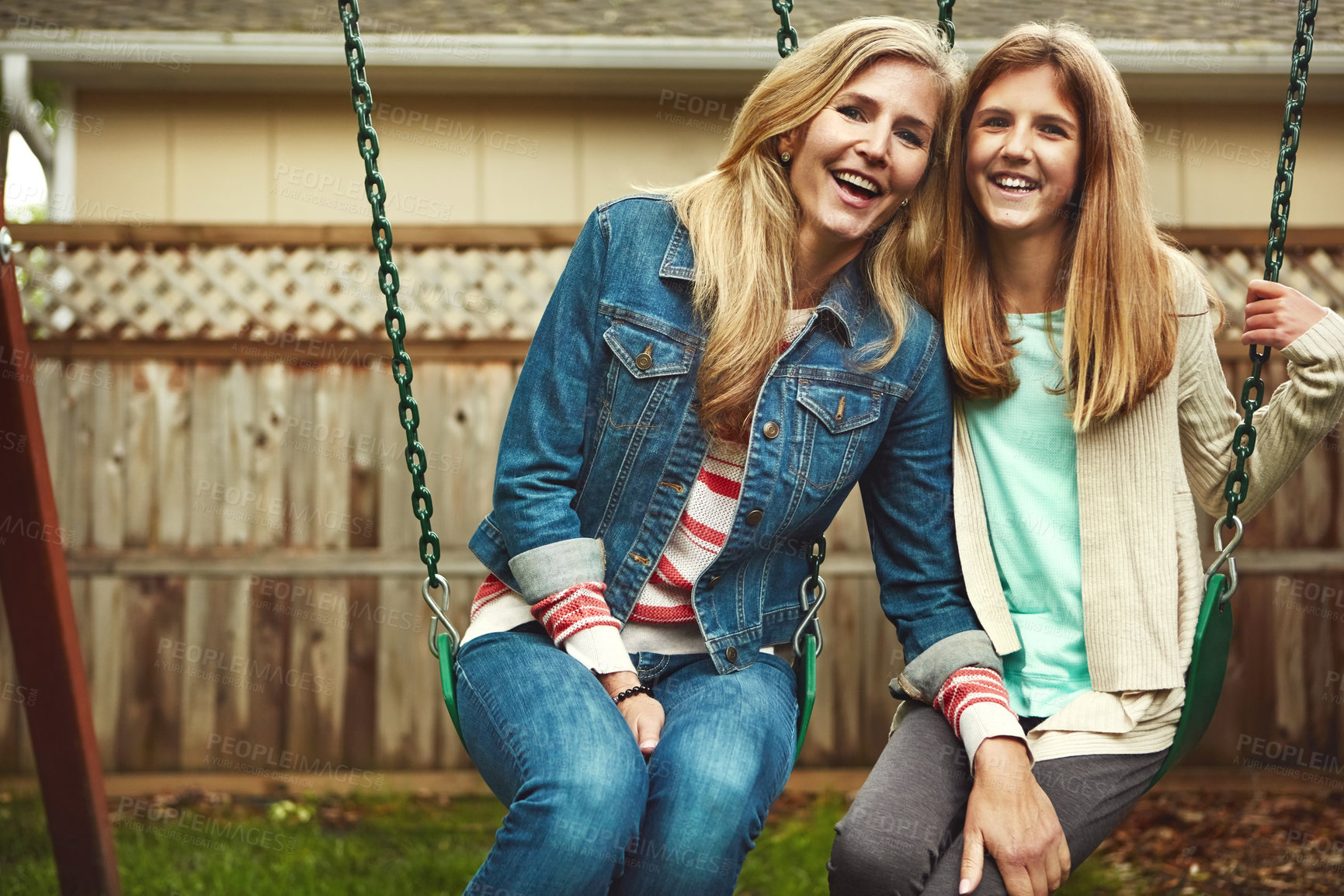 Buy stock photo Shot of a mother and her daughter playing on a swing in their backyard