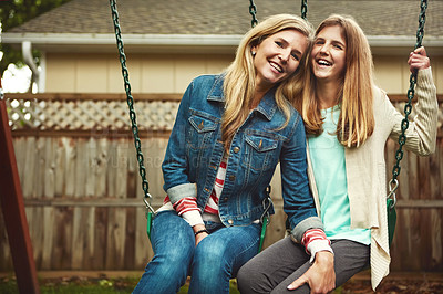 Buy stock photo Shot of a mother and her daughter playing on a swing in their backyard