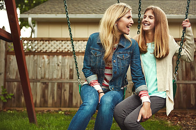 Buy stock photo Shot of a mother and her daughter playing on a swing in their backyard