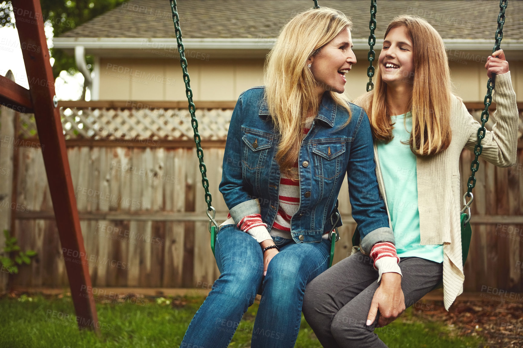 Buy stock photo Shot of a mother and her daughter playing on a swing in their backyard