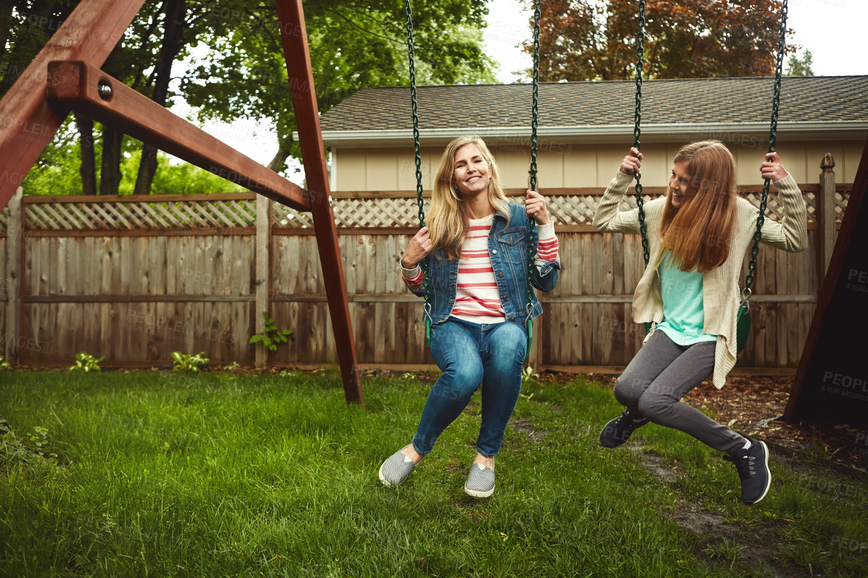 Buy stock photo Shot of a mother and her daughter playing on a swing in their backyard