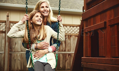 Buy stock photo Shot of a mother and her daughter playing on a swing in their backyard