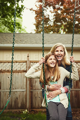 Buy stock photo Shot of a mother and her daughter playing on a swing in their backyard