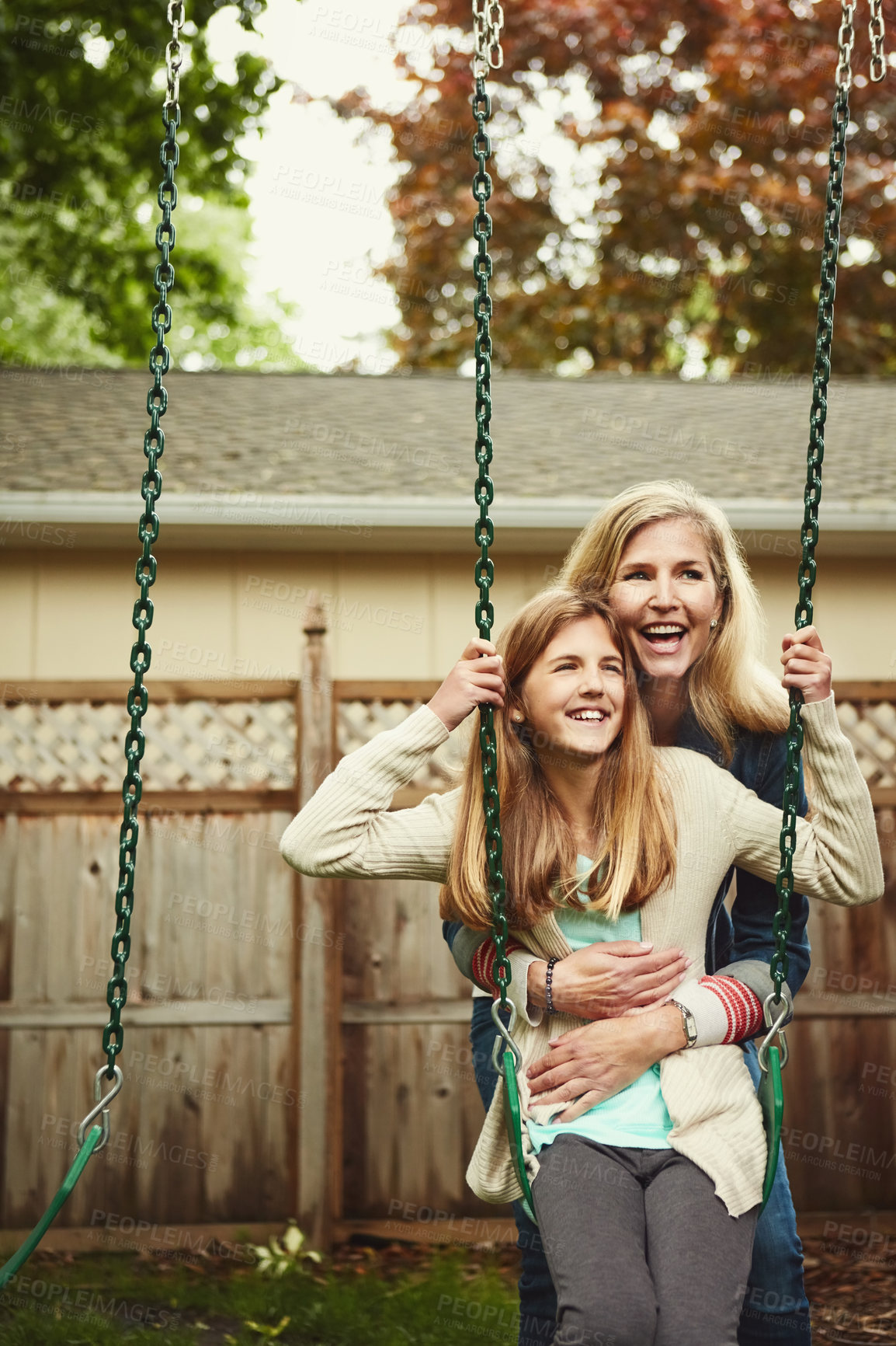 Buy stock photo Shot of a mother and her daughter playing on a swing in their backyard