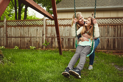 Buy stock photo Shot of a mother and her daughter playing on a swing in their backyard