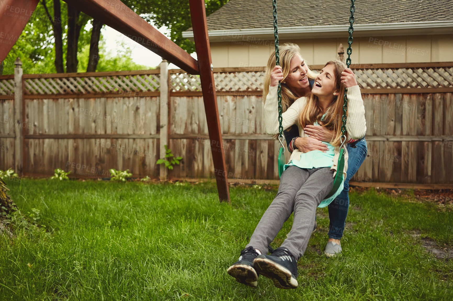 Buy stock photo Shot of a mother and her daughter playing on a swing in their backyard