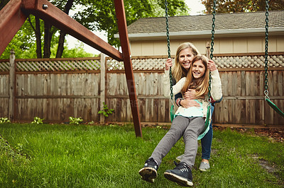 Buy stock photo Shot of a mother and her daughter playing on a swing in their backyard