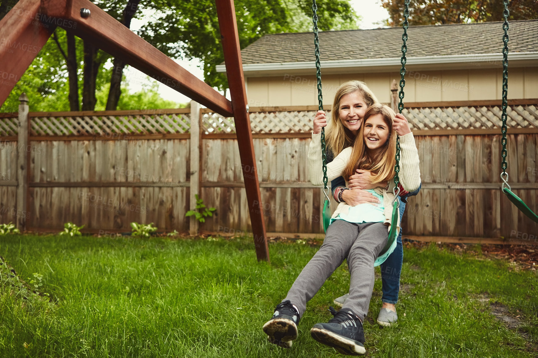 Buy stock photo Shot of a mother and her daughter playing on a swing in their backyard