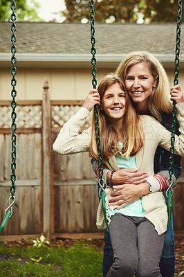 Buy stock photo Shot of a mother and her daughter playing on a swing in their backyard