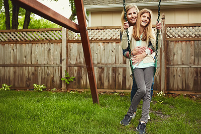 Buy stock photo Shot of a mother and her daughter playing on a swing in their backyard