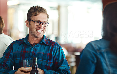 Buy stock photo Shot of young man enjoying a drink at a bar