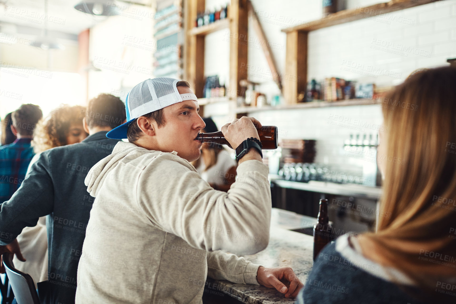 Buy stock photo Shot of a young man enjoying a drink at a bar