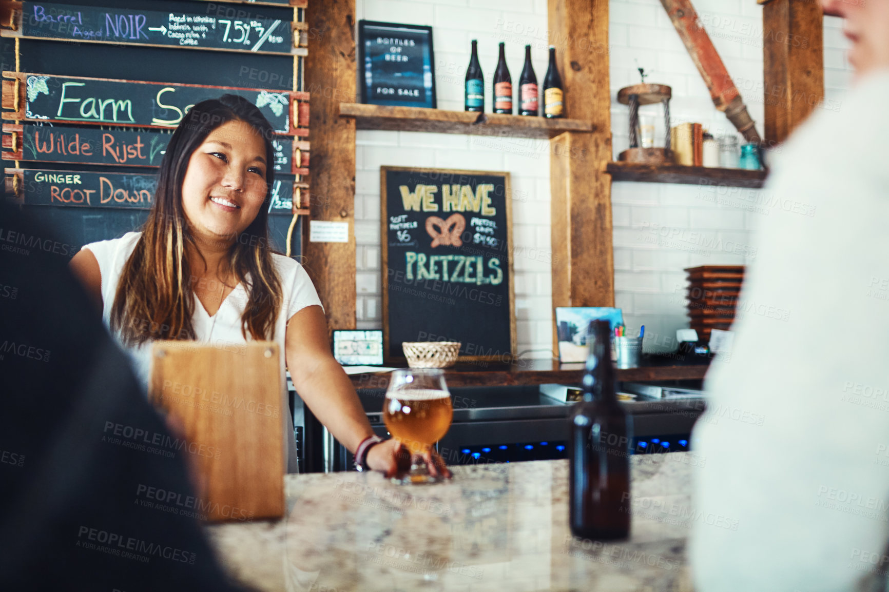 Buy stock photo Shot of a young woman serving drinks in a bar 