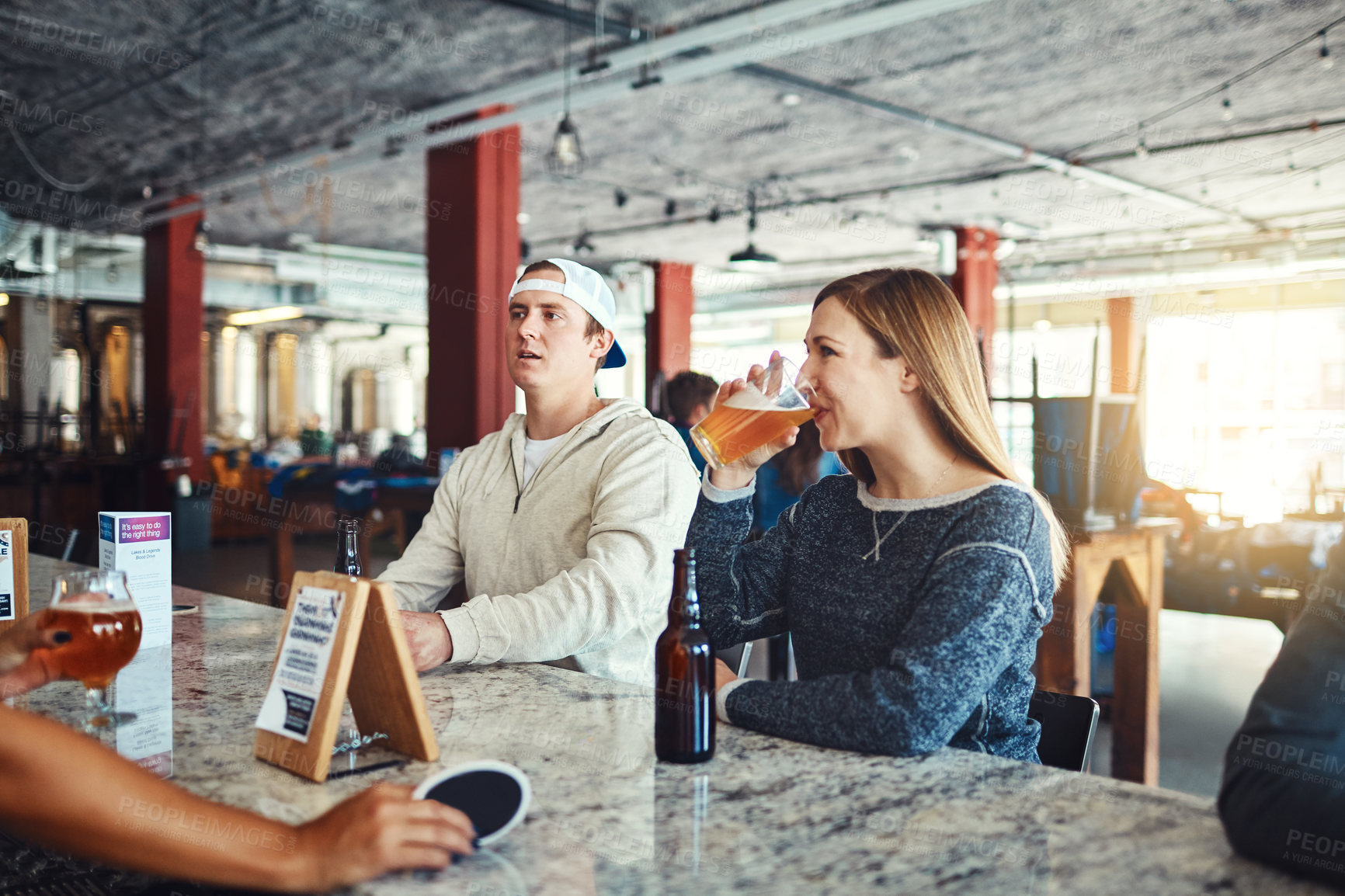 Buy stock photo Shot of a young couple enjoying a drink at a bar