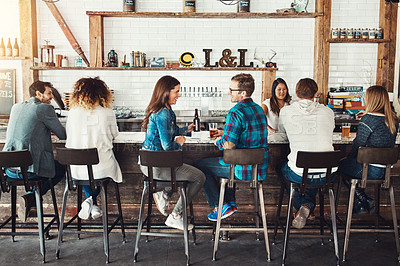 Buy stock photo Shot of young people enjoying a drink at a bar