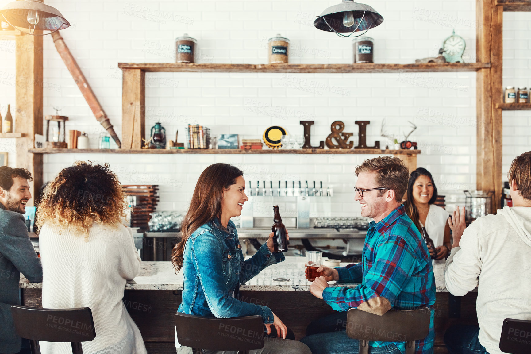 Buy stock photo Shot of a young couple enjoying a drink at a bar