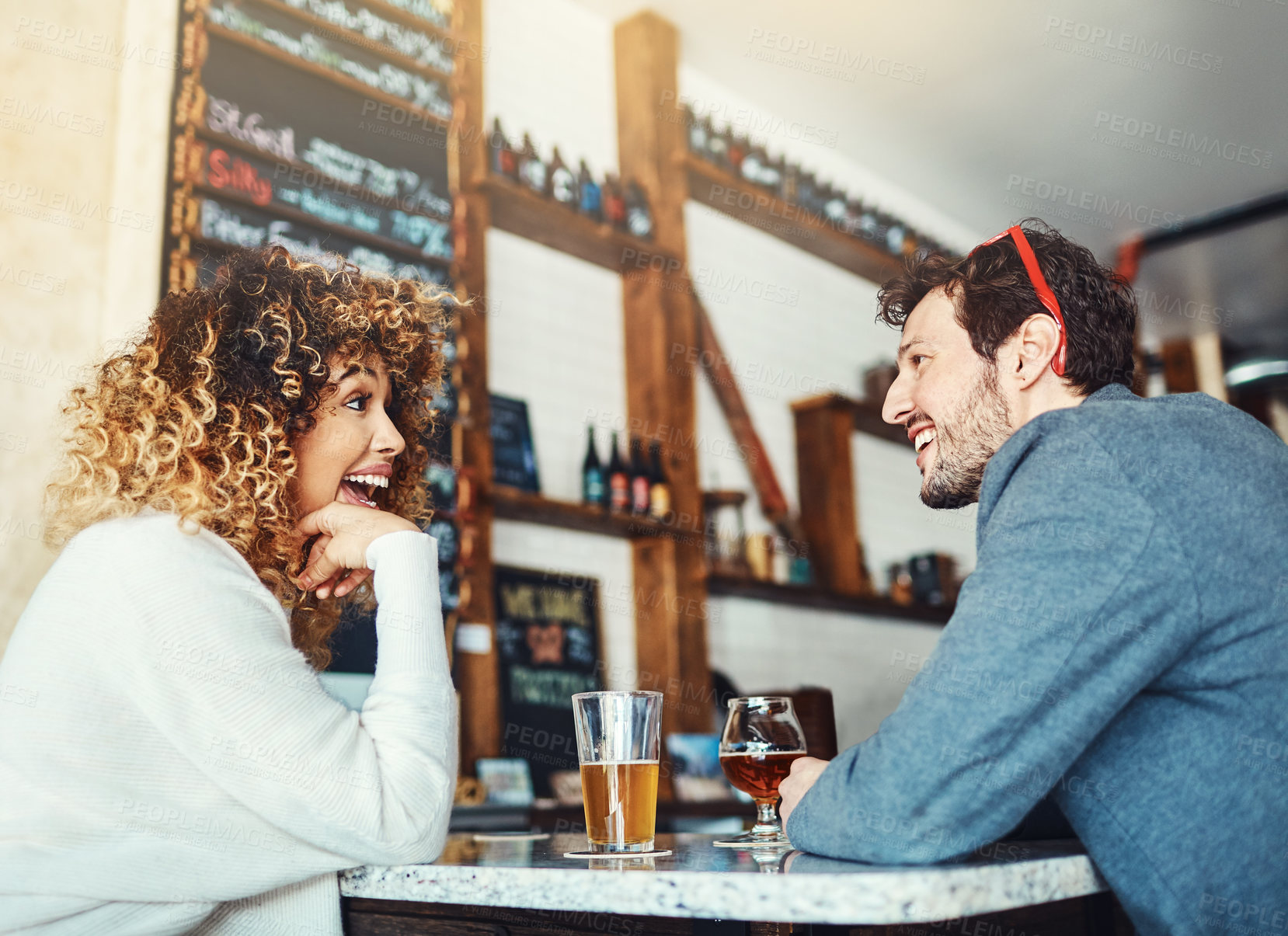 Buy stock photo Shot of a young couple enjoying a drink at a bar