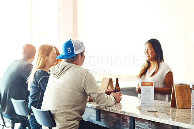 Buy stock photo Shot of a young woman serving drinks in a bar 