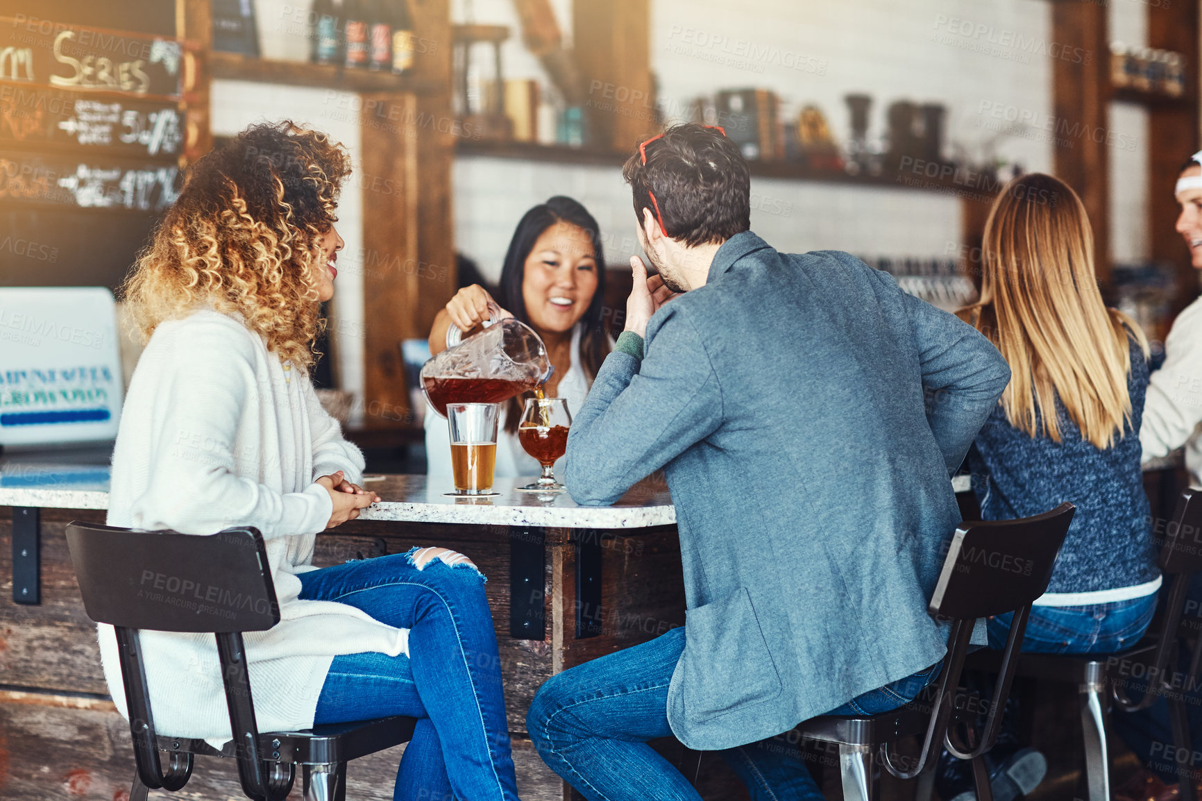 Buy stock photo Shot of a young woman serving drinks in a bar 