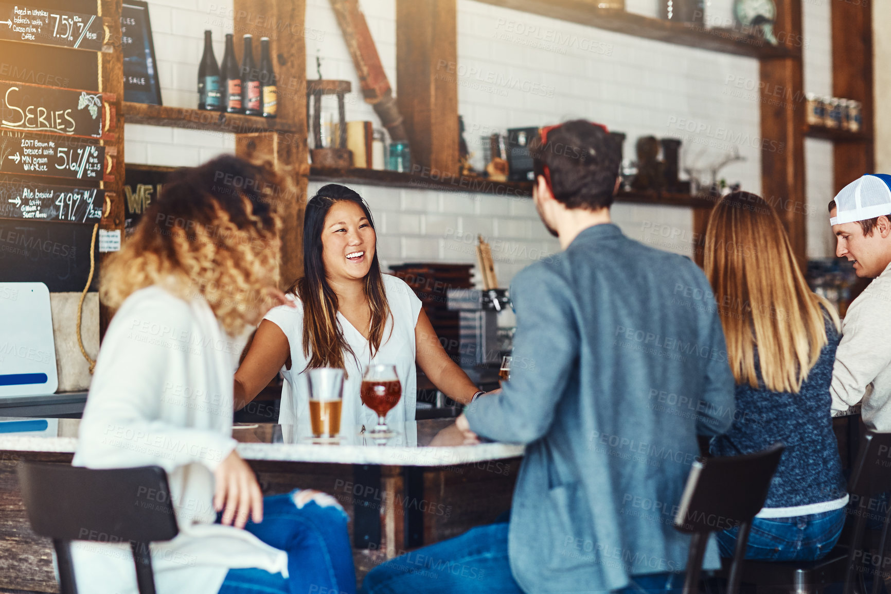 Buy stock photo Shot of a young woman serving drinks in a bar 