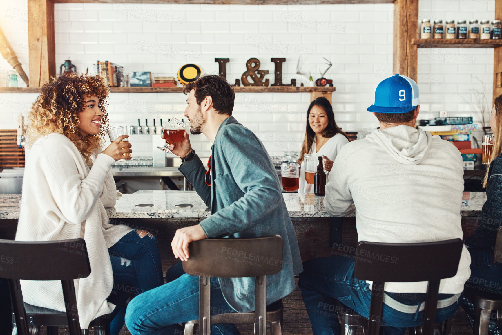 Buy stock photo Shot of a young couple enjoying a drink at a bar