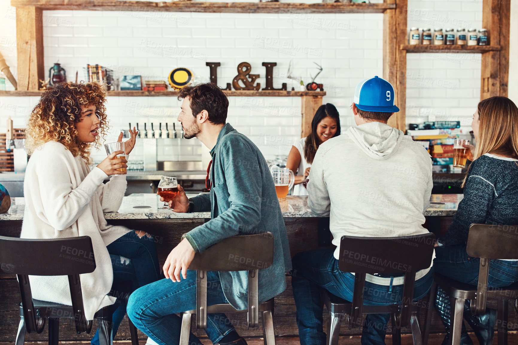 Buy stock photo Shot of young people enjoying a drink at a bar