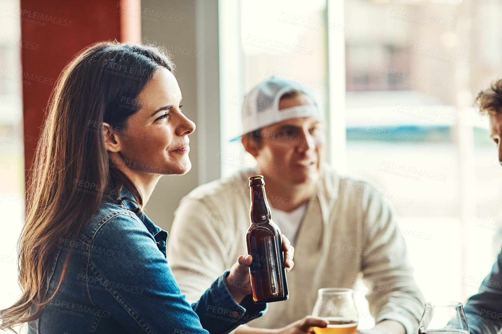 Buy stock photo Shot of a happy young woman enjoying the company in a bar