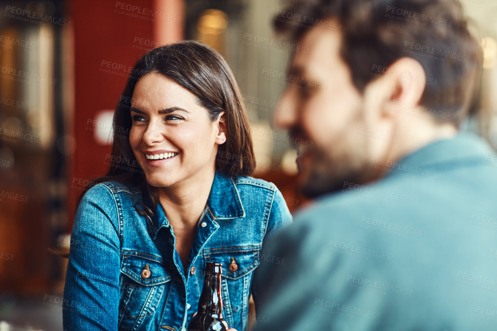 Buy stock photo Shot of a happy young woman enjoying the company in a bar