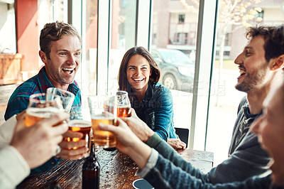 Buy stock photo Shot of a group of friends making a toast while enjoying themselves in a bar