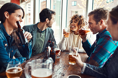 Buy stock photo Shot of young people having beers at a bar