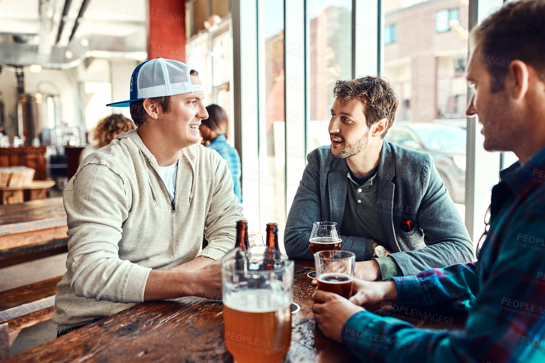 Buy stock photo Shot of three male friends having drinks in a bar